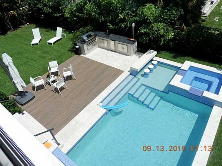 an aerial view of a swimming pool with lounge chairs and grill in the back yard