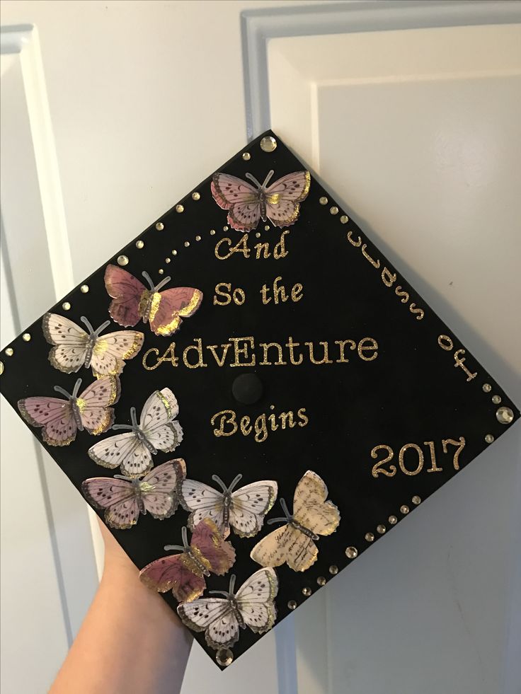 a black and gold graduation cap with butterflies on it that says and so the adventure begins