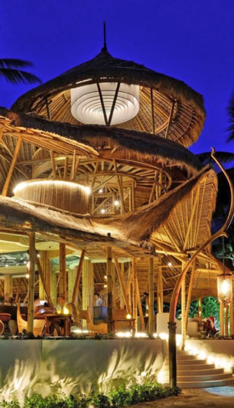 the outside of a restaurant at night with lights on and palm trees in the background