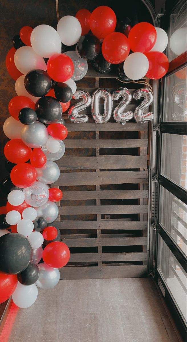 red, white and black balloons are hanging from the ceiling