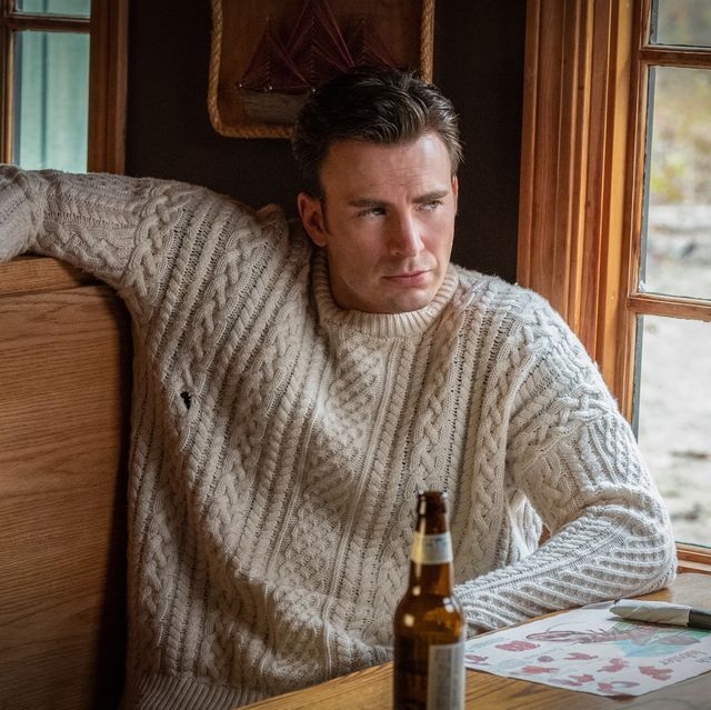 a man sitting at a table with a beer bottle in front of him and looking off into the distance