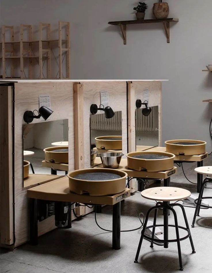 several tables and stools in a room with mirrors on the wall, one is made out of plywood