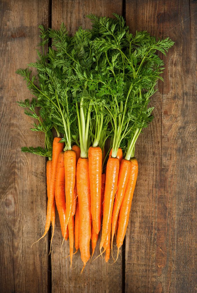 some carrots are laying on top of each other in the middle of a wooden table