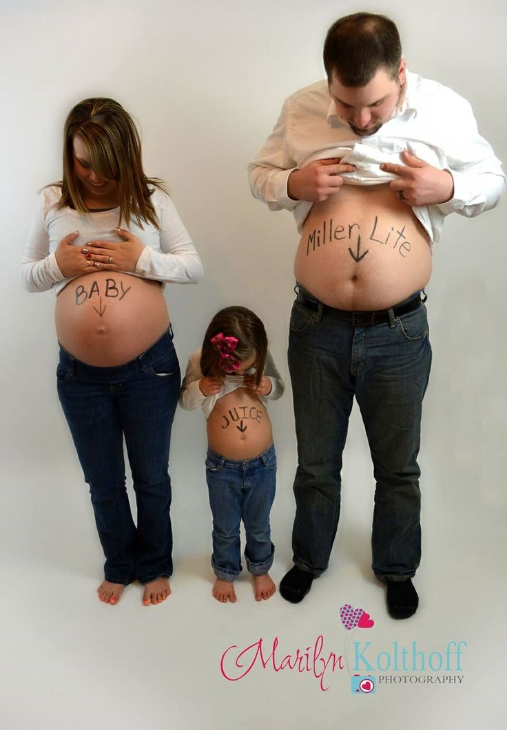 a man standing next to two women with their stomachs covered in writing on them