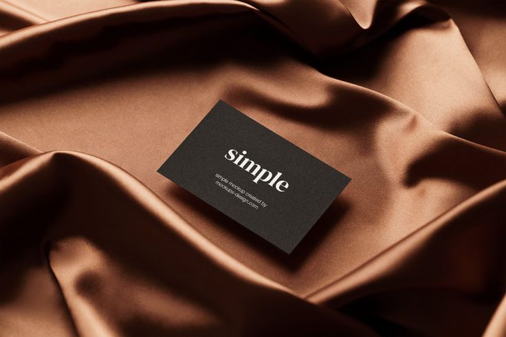 a business card sitting on top of a brown satin material covered in black and white text