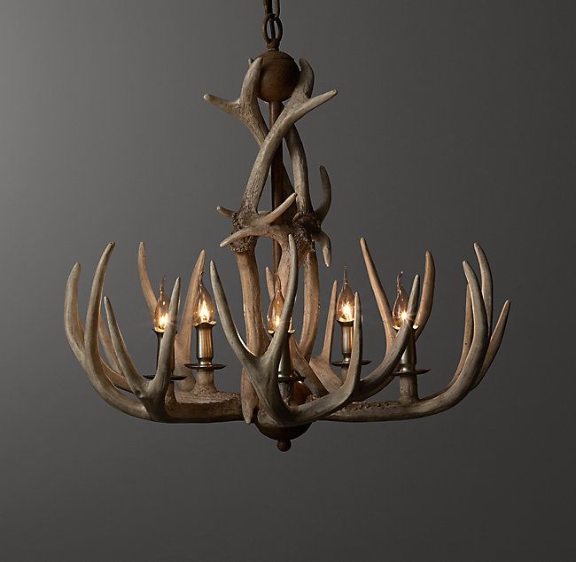 a chandelier with antlers hanging from it's sides and lit candles in the middle