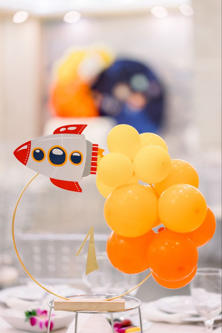 an orange balloon with a rocket ship on it and some other balloons in the background