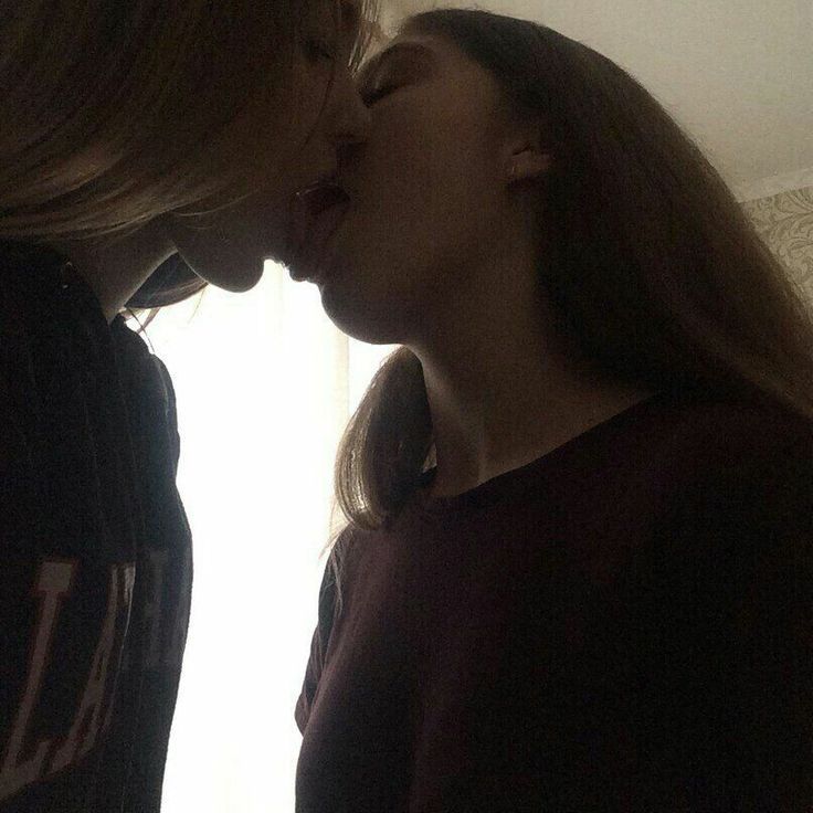 two women standing next to each other and one is kissing the other with her mouth open