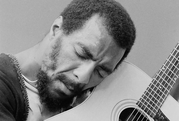 a man with a beard playing an acoustic guitar