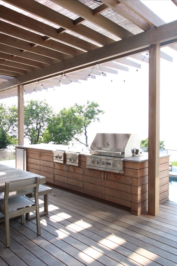 an outdoor kitchen with grill and table on the deck