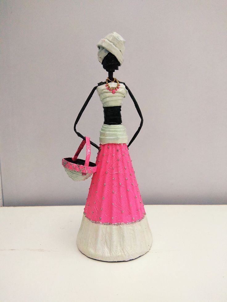 a figurine is holding a basket and wearing a pink dress with white trim