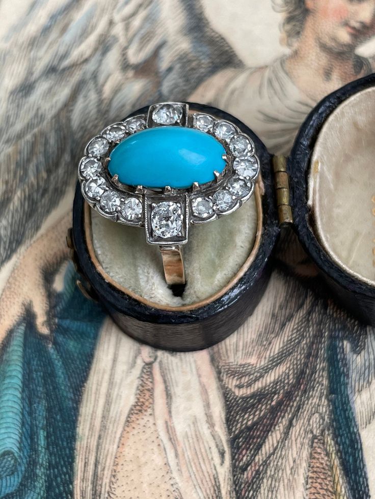 A bright robin's egg blue turquoise cabochon is perfectly framed in halo of sparkling single-cut and old mine-cut diamonds. This Edwardian treasure is crafted in platinum topped 14k yellow gold. Currently a finger size 4.5. Measurements: 18.80 x 17.12 mm Turquoise: 12.61 x 6.77 x 6.45 mm deep, lovely matrix on the back Diamonds: 14 single-cut diamonds estimated .50 total carats, two old mine-cut diamonds estimated .30 total carat weight. I-J range in color, SI2 - I1 range in clarity Metal: plati Oval Turquoise Ring With Diamond Accents, Turquoise Blue Diamond Ring With Center Stone, Gift Diamond Turquoise Cabochon Ring, Blue Diamond Turquoise Ring With Cabochon, Turquoise And Diamond Ring, Quartz Properties, Robin's Egg Blue, Quartz Crystal Necklace, Star Pictures