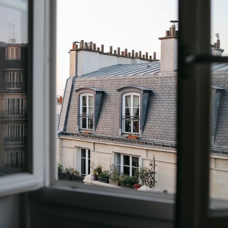 the view from an apartment building looking out at rooftops and windows with blue shutters