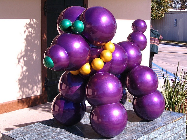 a large purple balloon sculpture sitting on top of a stone block in front of a building