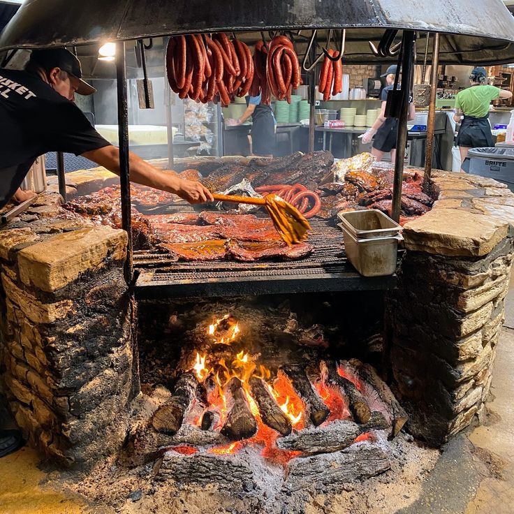 a man grilling hot dogs and sausages on an outdoor grill