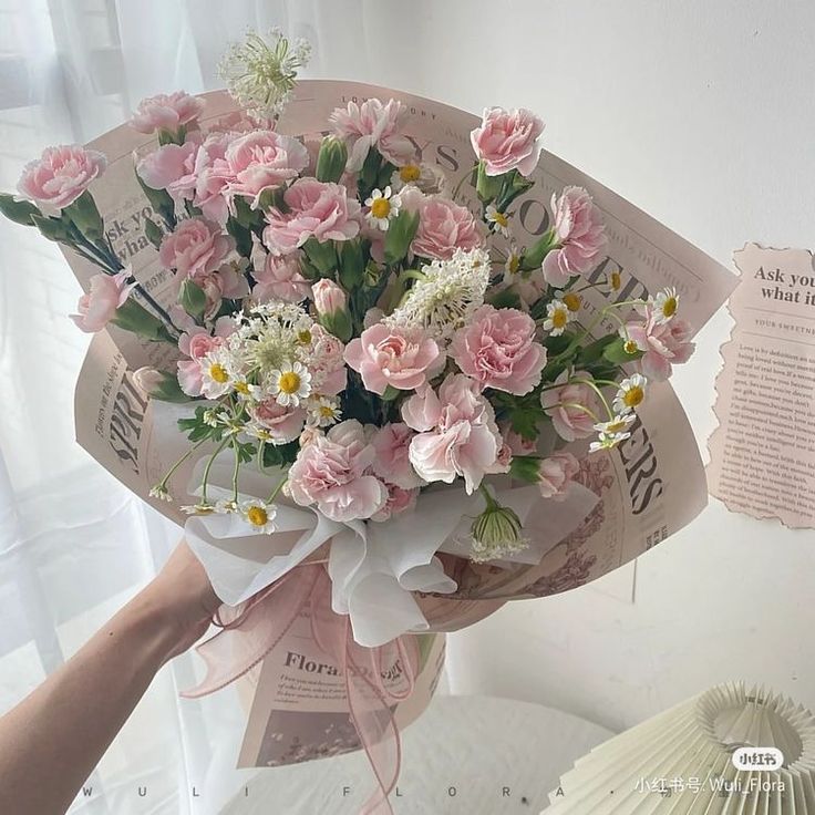 a bouquet of pink and white flowers in someone's hand