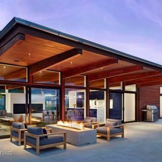 an outdoor living area with couches, chairs and a fire pit in the center