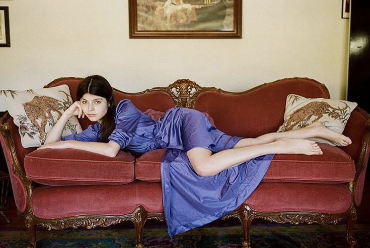 a woman laying on top of a red couch