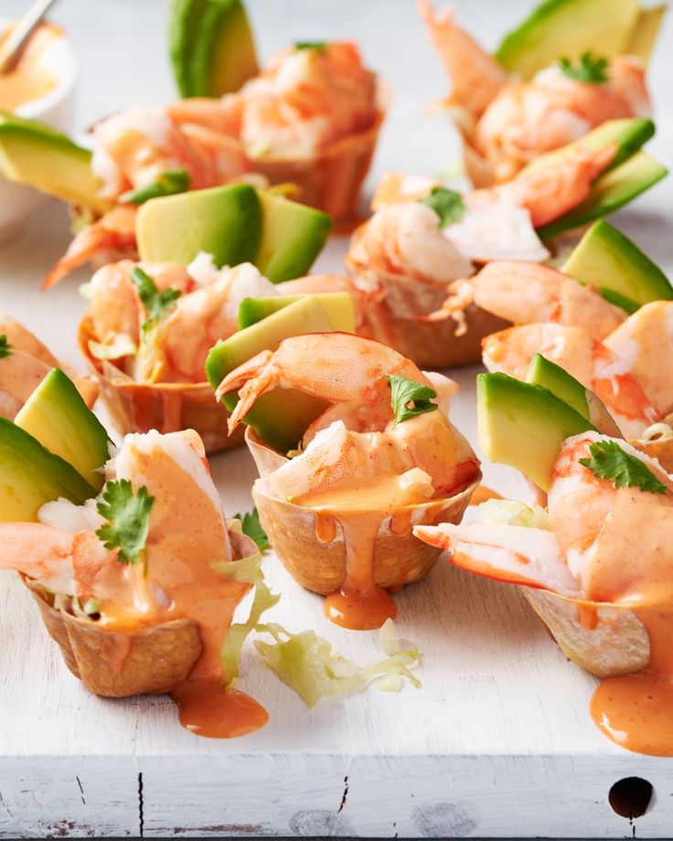 small appetizers with shrimp, avocado and sauce on a cutting board