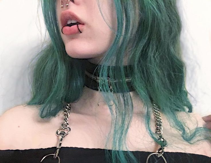 a woman with green hair and piercings on her nose is posing for the camera