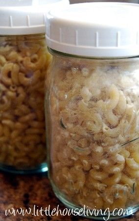 two jars filled with macaroni and cheese sitting on top of a wooden table