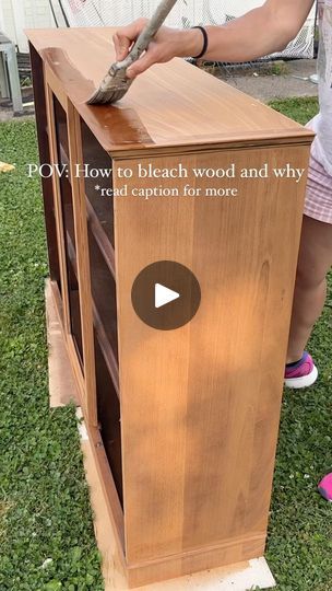 a woman is using a hammer to attach the top of a wooden cabinet on grass