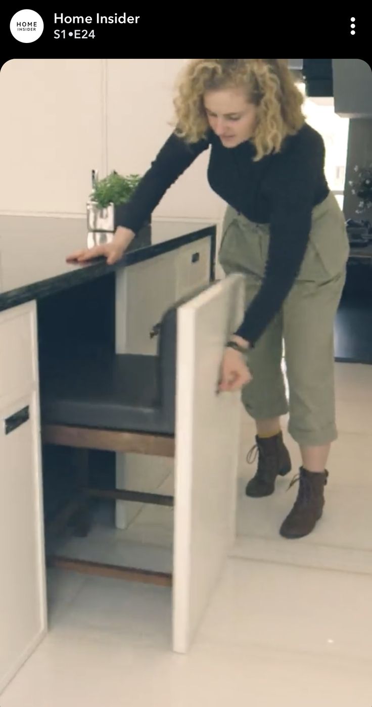 a woman standing at the top of a kitchen counter reaching into an open dishwasher