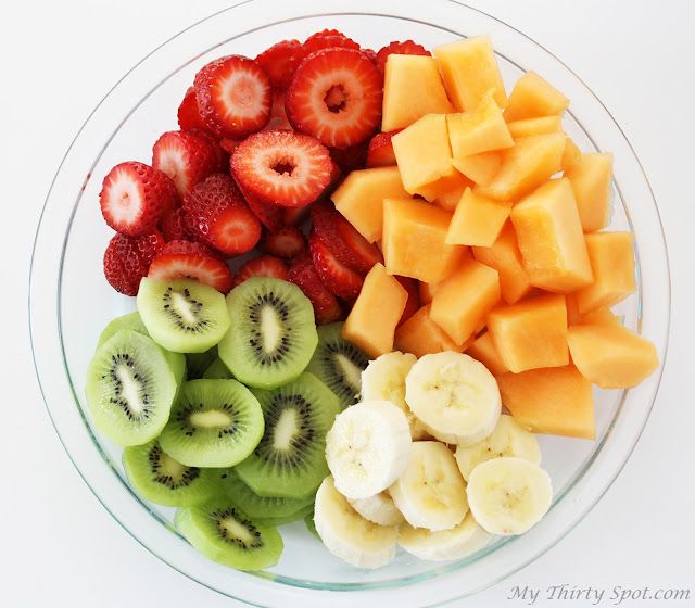 a bowl filled with cut up fruit like kiwis, bananas and strawberries