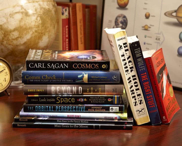 a stack of books sitting on top of a wooden table next to an alarm clock