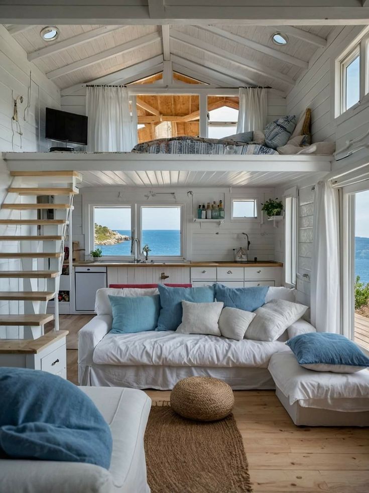 a living room filled with white furniture and lots of blue pillows on top of it