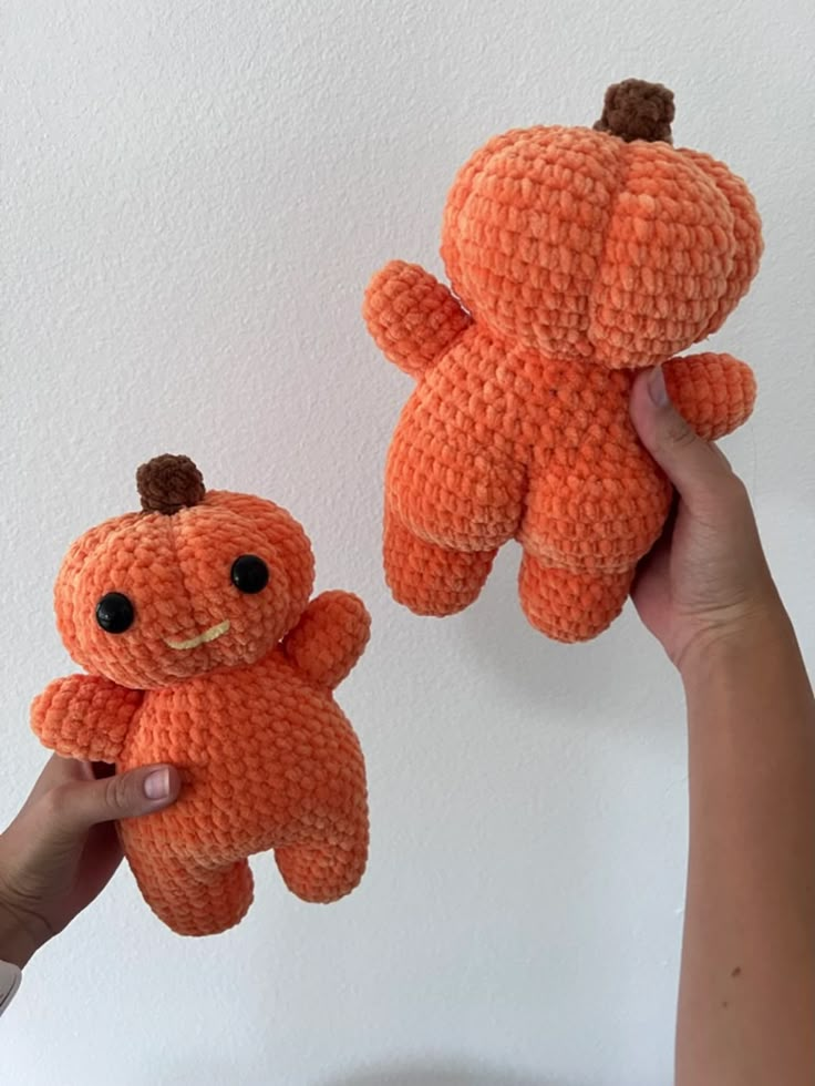 two small orange teddy bears are being held up