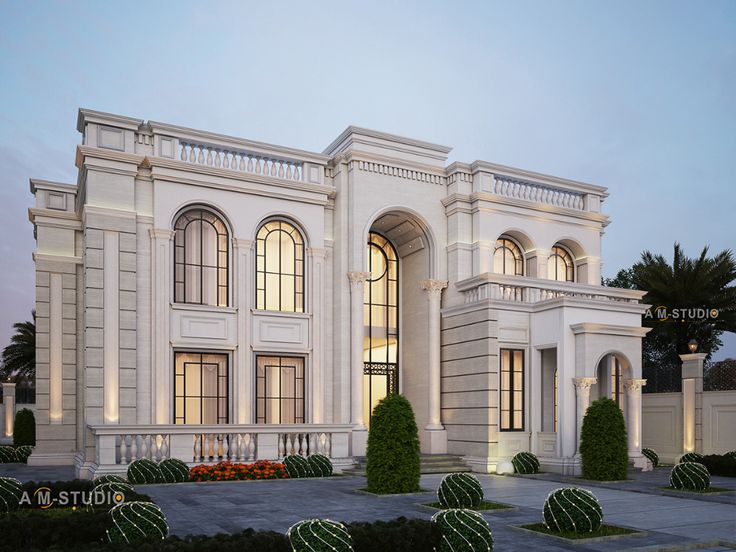 a large white building with lots of windows and bushes in front of it at dusk