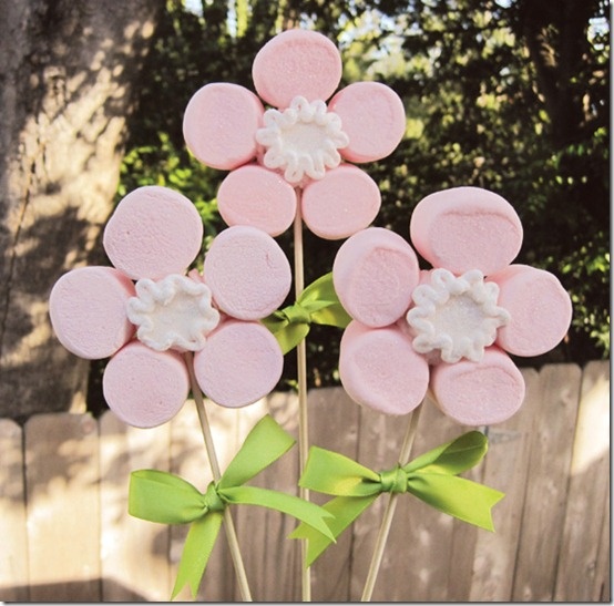 pink and white candy flowers in a vase on a wooden table with fence behind them