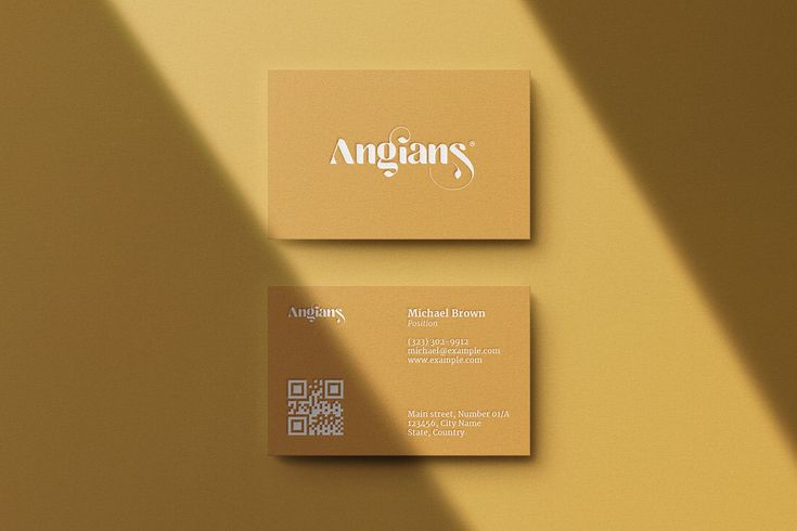 two business cards sitting next to each other on top of a yellow wall with the word anggars printed on it