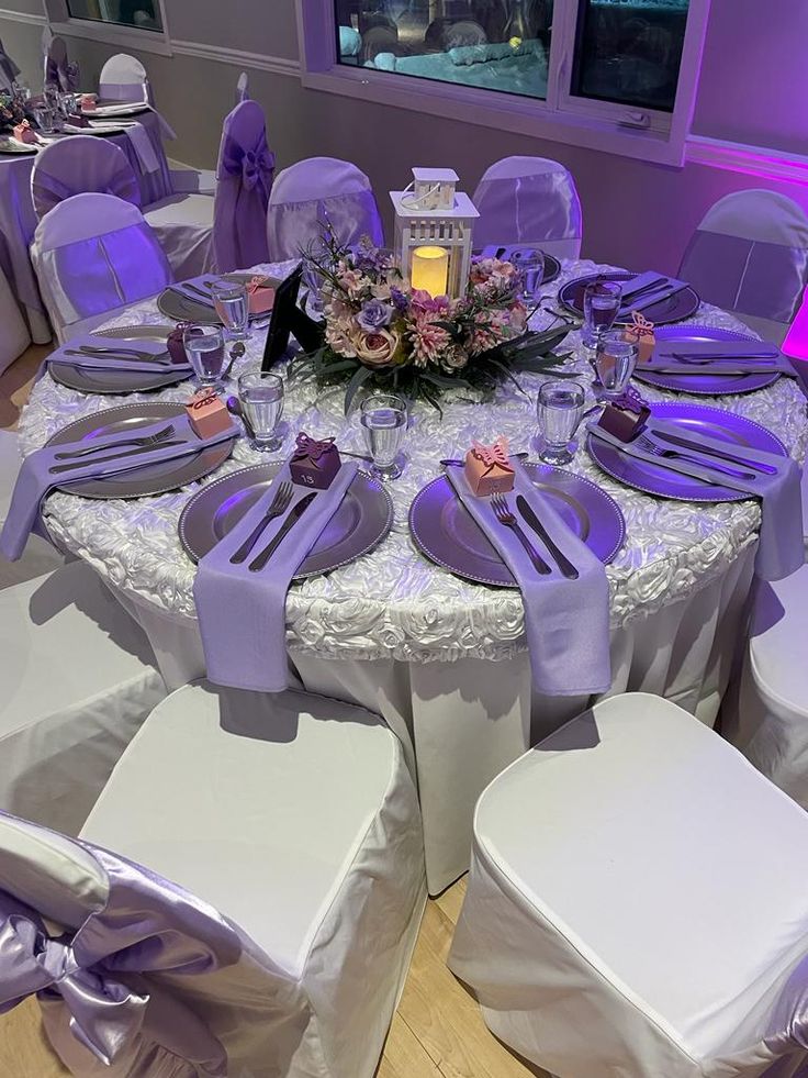 the table is set with purple and white linens