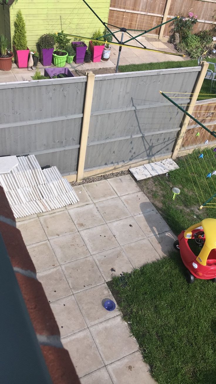 a small child's toy car sitting in the grass next to a backyard fence