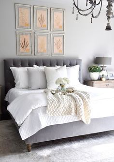 a bed with white sheets and pillows in a bedroom next to pictures on the wall