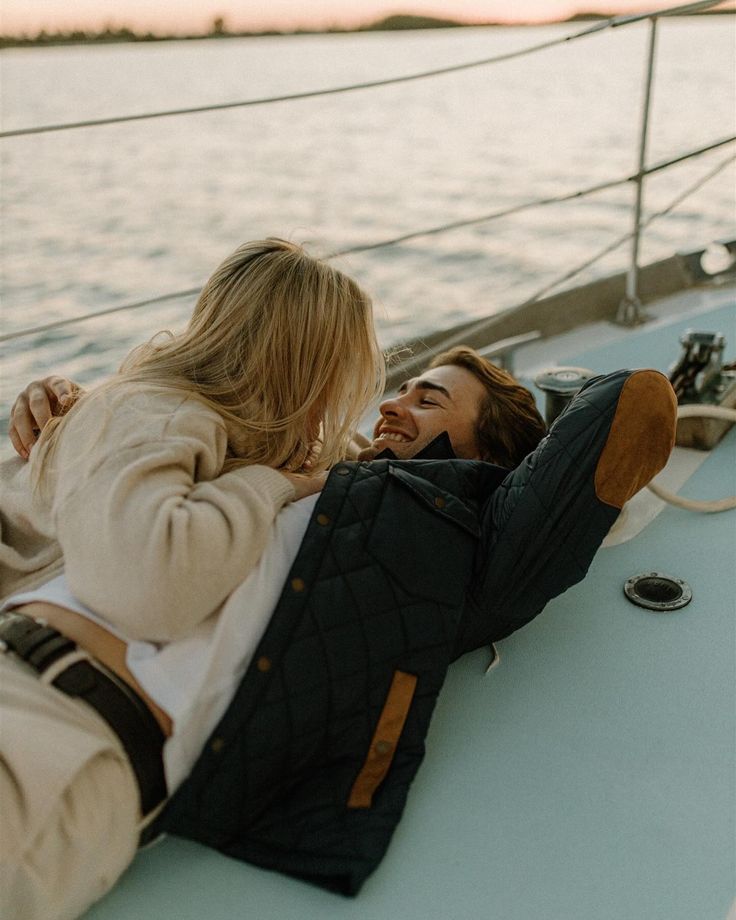 two women are sitting on the back of a boat and smiling at each other as they look out over the water