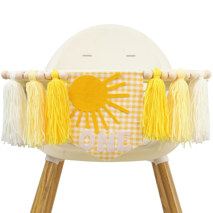 a yellow and white chair with tassels on it