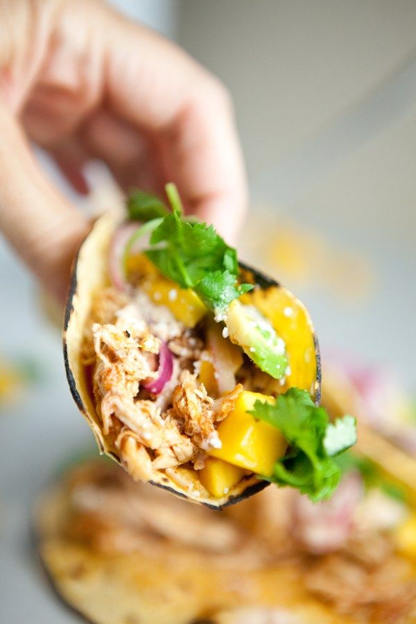 a person is holding a burrito with meat and vegetables