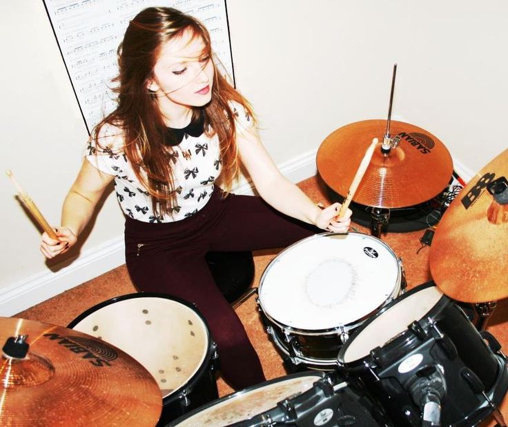 a girl is playing drums on the floor