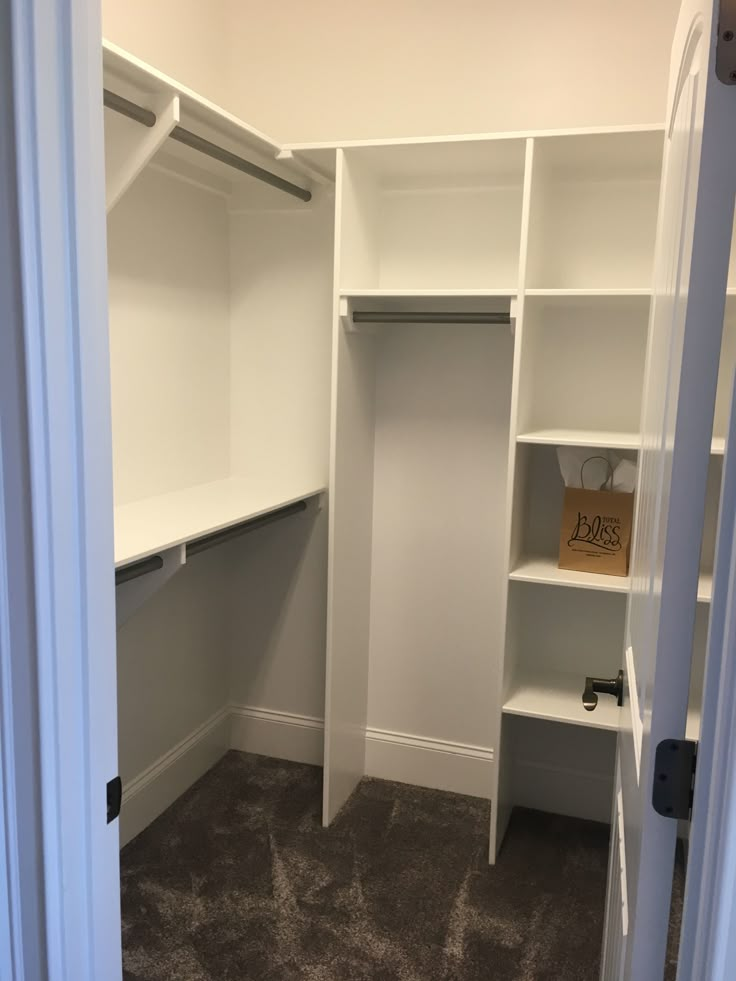 an empty walk in closet with white shelves and carpeted flooring on the ground