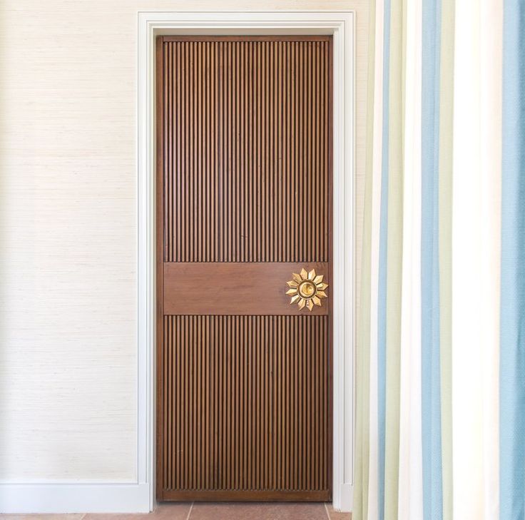 an open door with a wooden handle on it in a room that has striped walls and tile flooring