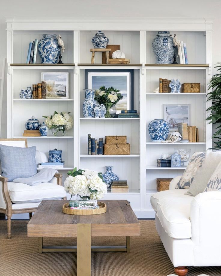 a living room filled with white furniture and lots of blue and white decor on the walls