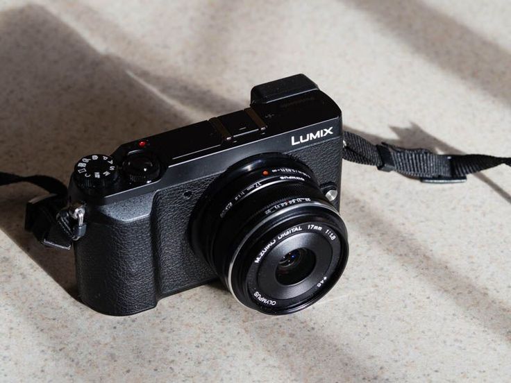 a black camera sitting on top of a table next to a white wall and floor