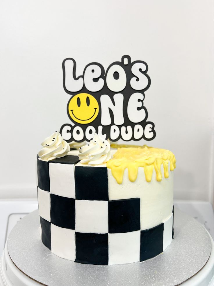 a black and white checkerboard cake with yellow icing on top that says leo's one cool dude