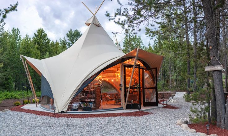 a white tent sitting in the middle of a forest