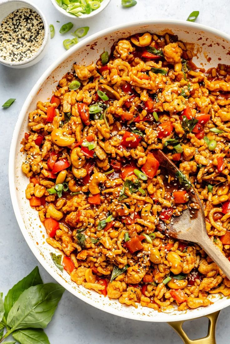 a skillet filled with pasta and vegetables on top of a white table next to other dishes