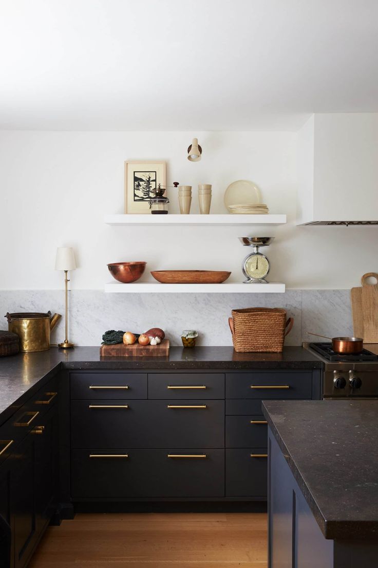 a kitchen with black cabinets and gold accents on the counter tops, along with an open shelving unit