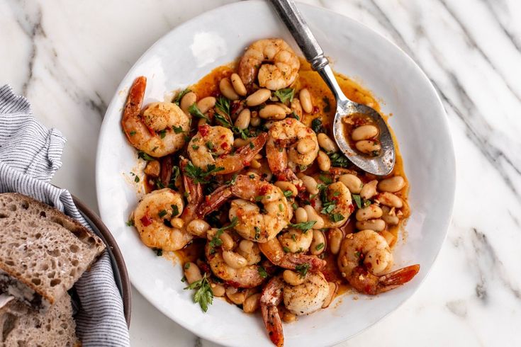 a white plate topped with shrimp next to bread